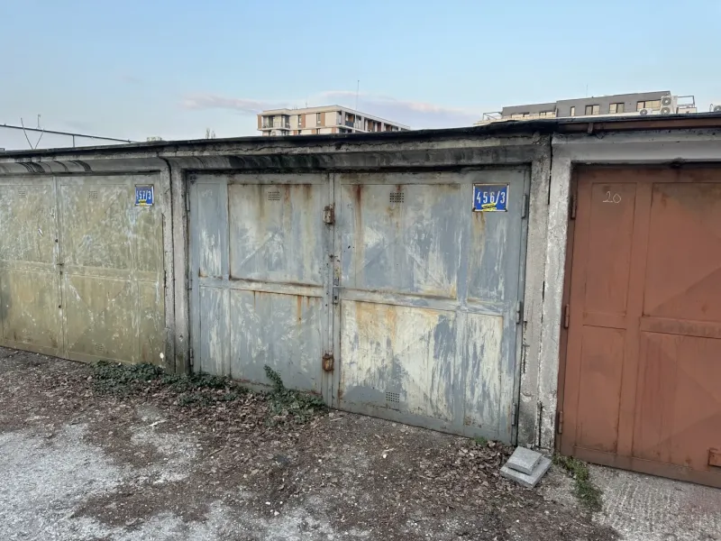 18 m2 Garáž na Sliačskej ulici v Bratislave - Opustené garáže v Bratislave - Novom Meste s opadanou omietkou a plechovými dverami.