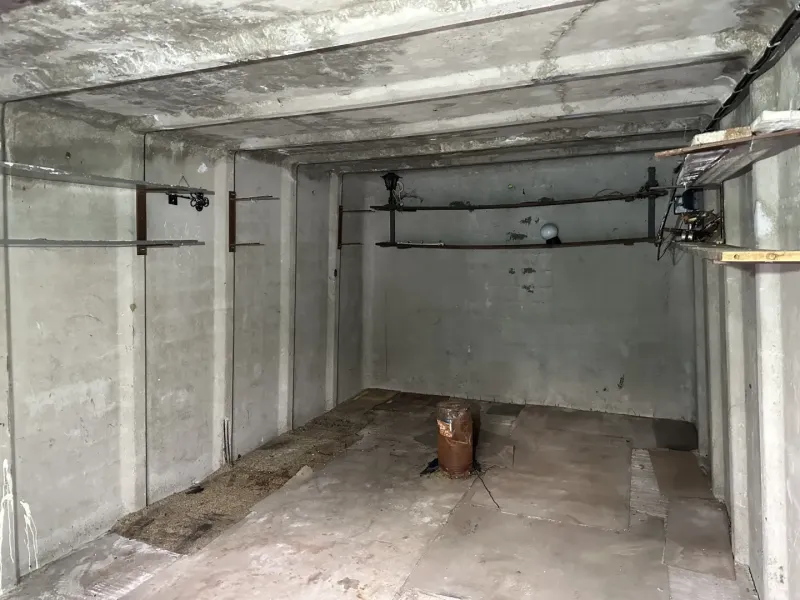 18 m2 Garáž na Sliačskej ulici v Bratislave - Prázdna betónová miestnosť s trubkami a osvetlením, interiér garáže.