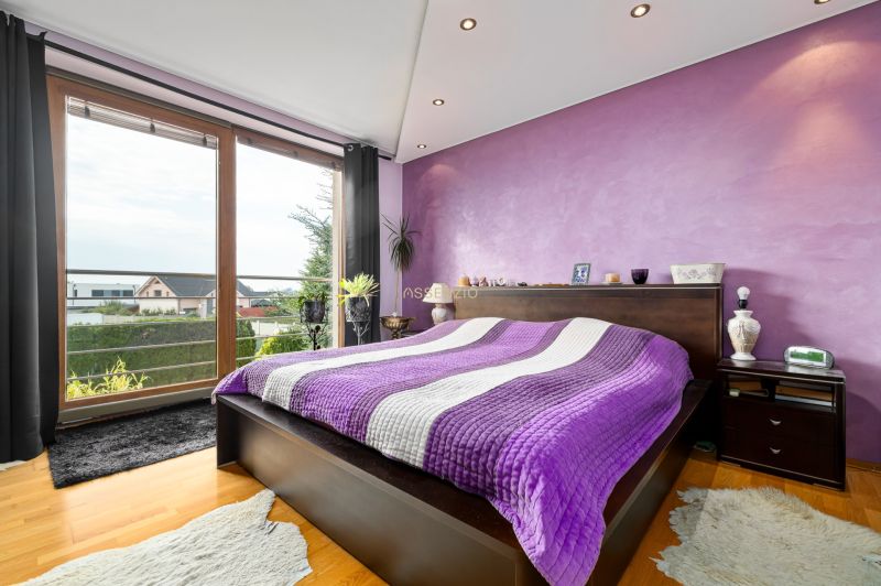 4 izbový rodinný dom Nová Dedinka, predaj, 543m2  - Štýlová spálňa s fialovou stenou a výhľadom, podlaha s dreveným dekorom.