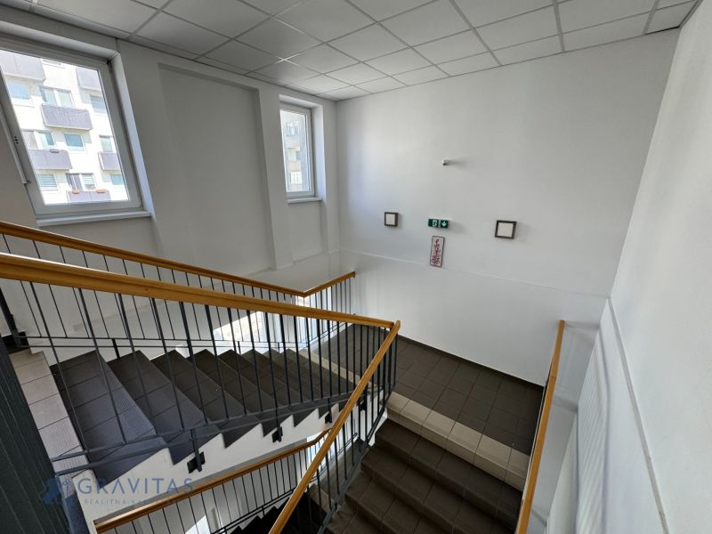 Zariadený 1-izbový byt na predaj, Podunajské Biskupice - Schodisko s oknami a zábradlím v budove na ulici Podunajská, Bratislava - Podunajské Biskupice.