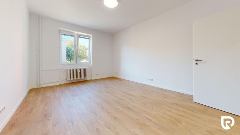 3,5-izb. byt 82 m2 | Drieňová ul.Štrkovec | komplet rek. - Priestranná izba so svetlými stenami, podlahou s dreveným dekorom a veľkým oknom.