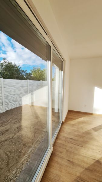 / Novostavba, moderný bungalov, dokončený na kľúč  - Svetlá izba rodinného domu s posuvnými dverami a podlahou s dreveným dekorom.
