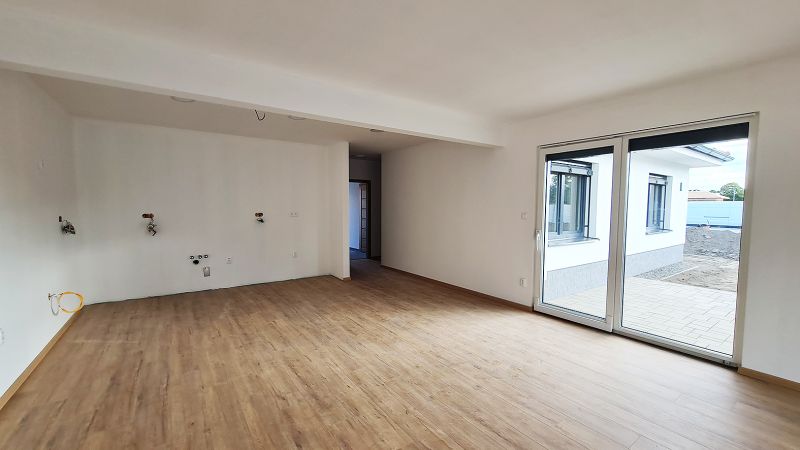 / Novostavba, moderný bungalov, dokončený na kľúč  - Rodinný dom s priestrannou miestnosťou, podlahou s dreveným dekorom a veľkými posuvnými dverami.