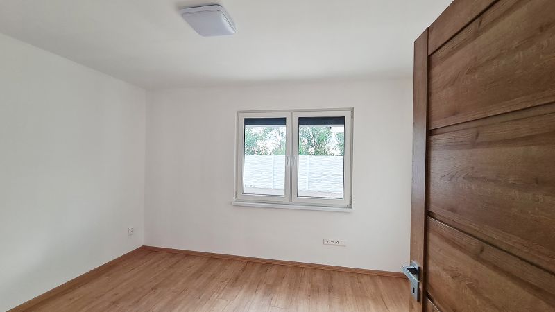 / Novostavba, moderný bungalov, dokončený na kľúč  - Izba v rodinnom dome s podlahou s dreveným dekorom a veľkým oknom.