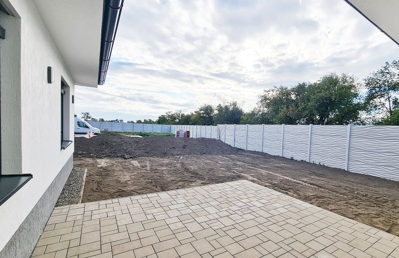 / Novostavba, moderný bungalov, dokončený na kľúč  - Rodinný dom v Senci s dlažbou a bielym plotom, vhodný pre pokojné bývanie.