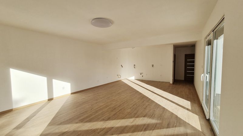 / Novostavba, moderný bungalov, dokončený na kľúč  - Interiér rodinného domu s podlahou s dreveným dekorom a veľkými oknami.