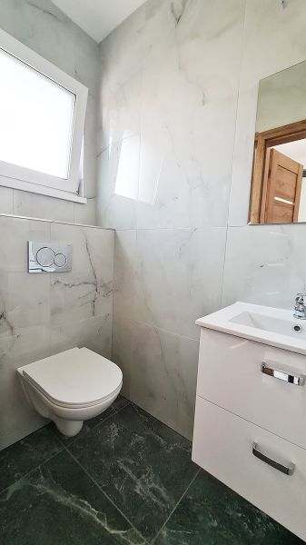 / Novostavba, moderný bungalov, dokončený na kľúč  - Kúpeľňa v rodinnom dome s podlahou s dreveným dekorom a bielym sanitárnym vybavením.