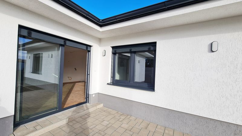 / Novostavba, moderný bungalov, dokončený na kľúč  - Exteriér rodinného domu v Senci s terasou a veľkými sklenenými dverami.