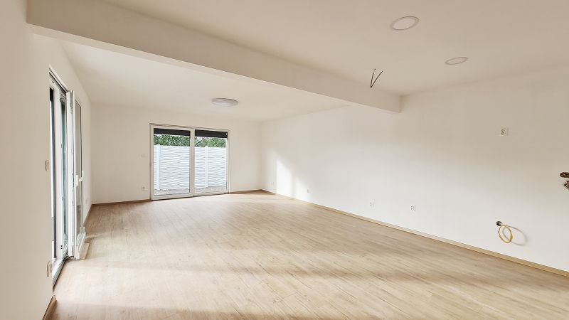 / Novostavba, moderný bungalov, dokončený na kľúč  - Priestranný interiér rodinného domu s podlahou s dreveným dekorom a veľkým oknom.