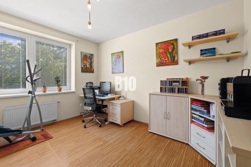 PRIESTRANNÝ 4-IZBOVÝ BYT S DVOMA BALKÓNMI | KRAMÁRE – ul. UHROVA - Pracovňa so stolom, kvetmi a cvičebným zariadením v 4-izbovom byte s podlahou s dreveným dekorom.