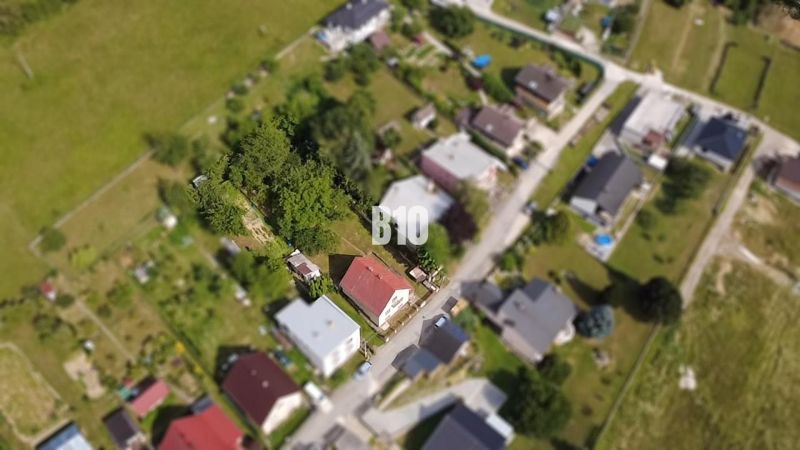 Rodinný dom s veľkým pozemkom a nádhernými výhľadmi – Dolný Milochov - Letecký pohľad na rodinný dom v Považskej Bystrici obklopený zeleňou a ďalšími domami.