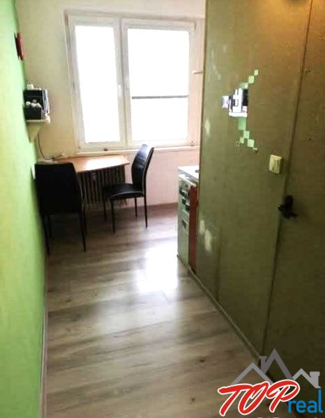 1- izbový byt - Košice - Juh, Ostravská ulica - Kuchyňa v 1-izbovom byte s dreveným dekorom podlahy a stolíkom pri okne.