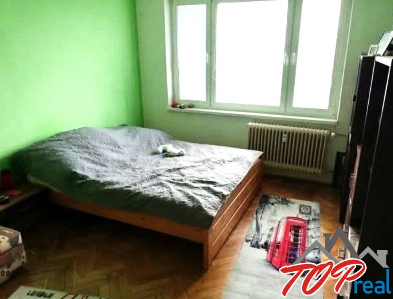 1- izbový byt - Košice - Juh, Ostravská ulica - Spálňa v 1-izbovom byte so zelenou stenou a podlahou s dreveným dekorom.