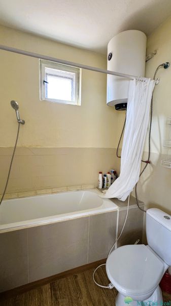 Dve generácie pod jednou strechou, Novosad, rodinný dom, 99.000€ - Kúpeľňa s vaňou, sprchou, bojlerom a podlahou s dreveným dekorom v rodinnom dome.