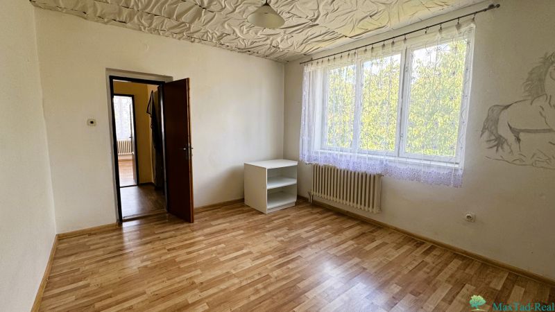 Dve generácie pod jednou strechou, Novosad, rodinný dom, 99.000€ - Izba s podlahou s dreveným dekorom, skrinkou a maľbou na stene v rodinnom dome.