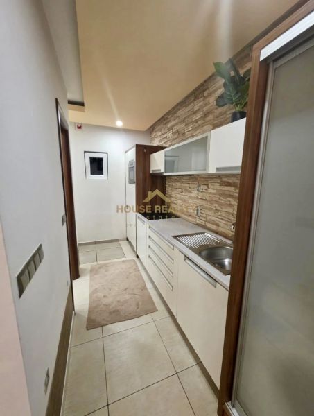 Novostavba 1 izbový byt, Sklenárska cesta, Bratislava I. Staré Mesto - Úzka kuchyňa v 1-izbovom byte s bielymi skriňami a dekoračnými obkladmi.