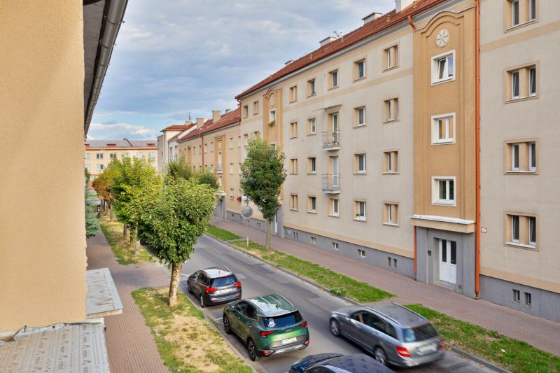 NOVÁ GARSÓNKA V CENTRE - MINÚTU OD NÁMESTIA - Ulica Študentská v Zvolene s bytovými domami a prechádzajúcimi autami, vhodná pre garsónku.