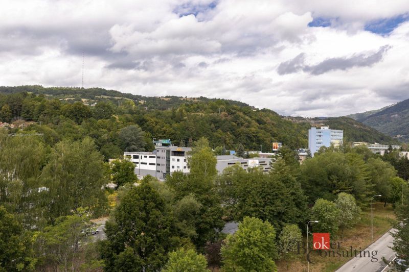 Na predaj luxusný 2-izbový byt, výnimočná terasa pre náročných - Výhľad na zeleň a budovy v Banskej Bystrici na Severnej ulici, obklopené kopcami.
