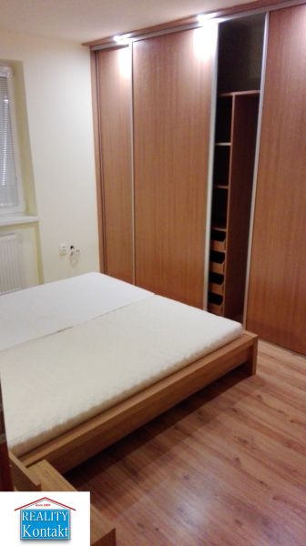 Na prenájom 3-izbový byt so záhradkou v Nových Zámkoch - Spálňa s podlahou s dreveným dekorom a vstavanou skriňou v 3-izbovom byte.