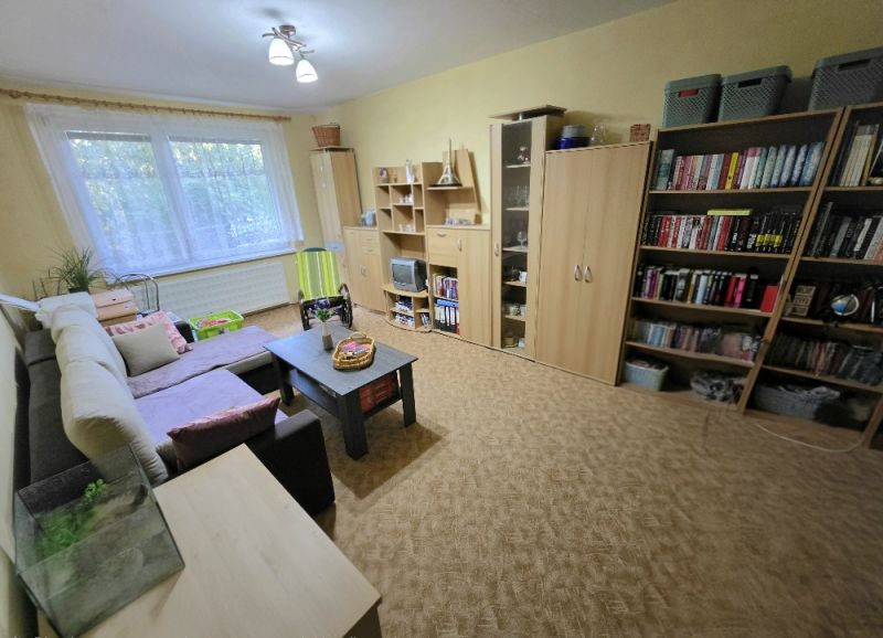 4 izbový byt Bánovce nad Bebravou /CENTRUM - STRED / 80 m2/ PIVNICA - Obývačka v 4-izbovom byte s veľkou pohovkou, stolíkom a knižnicou.