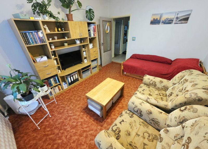 4 izbový byt Bánovce nad Bebravou /CENTRUM - STRED / 80 m2/ PIVNICA - Obývacia izba v 4-izbovom byte so sedačkou, červeným sedacím zákutím a stenovou policou.