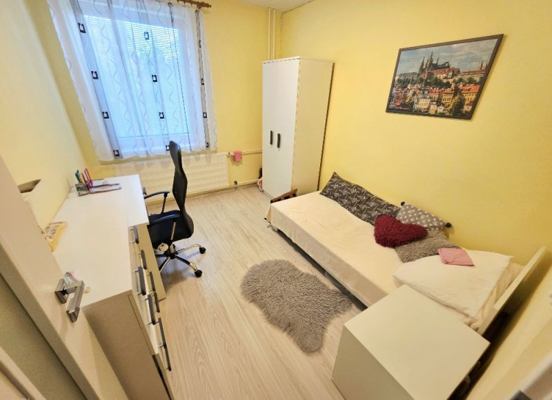 4 izbový byt Bánovce nad Bebravou /CENTRUM - STRED / 80 m2/ PIVNICA - Žltá izba s jedným lôžkom, pracovným stolom a podlahou s dreveným dekorom v 4-izbovom byte.