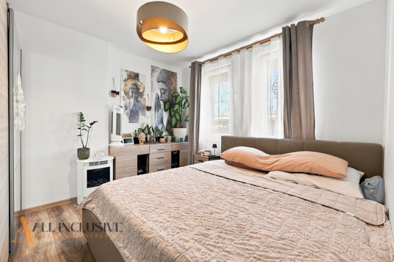 Na predaj moderný 3-izbový radový rodinný dom, Oľdza - Spálňa so svetlými stenami, posteľou a dekoráciami, podlaha s dreveným dekorom.