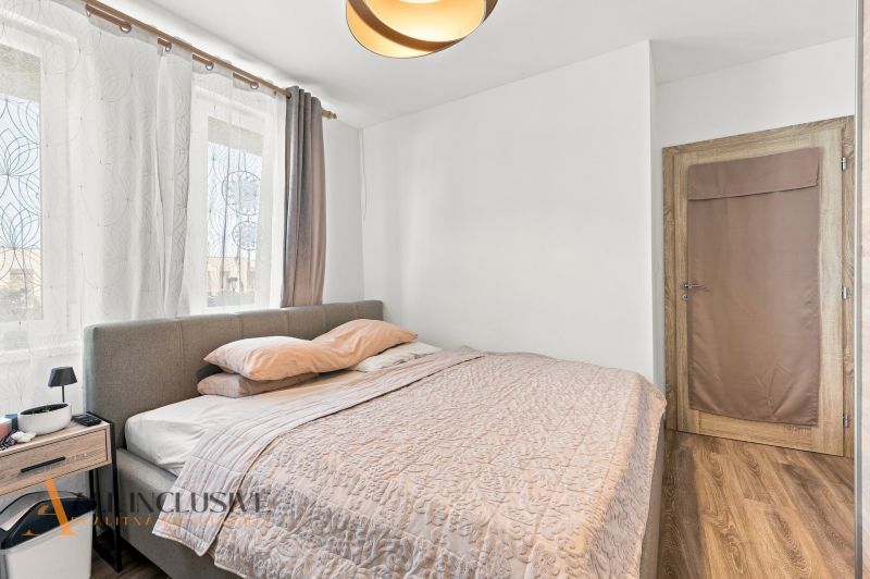 Na predaj moderný 3-izbový radový rodinný dom, Oľdza - Spálňa v rodinnom dome s podlahou s dreveným dekorom, sivou posteľou a závesmi.