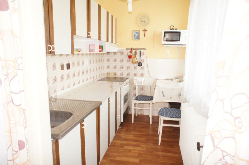 Rodinný dom v BA IV - Záhorská Bystrica, ul. Donská - Kuchyňa v rodinnom dome s podlahou s dreveným dekorom, jedálenským stolom a spotrebičmi.