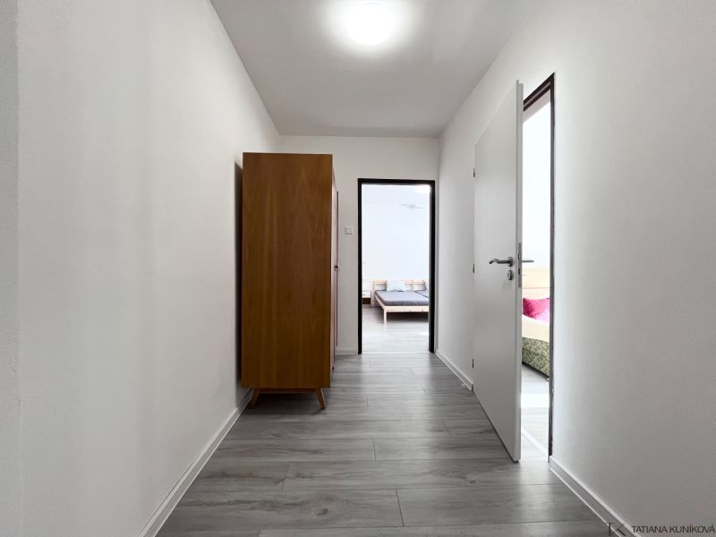 NA PRENÁJOM! Slnečný a zariadený 3i byt 68 m2, ul. Švermova, Trenčín - Chodba s podlahou s dreveným dekorom v 3-izbovom byte, tmavá skriňa, dvere do izieb.
