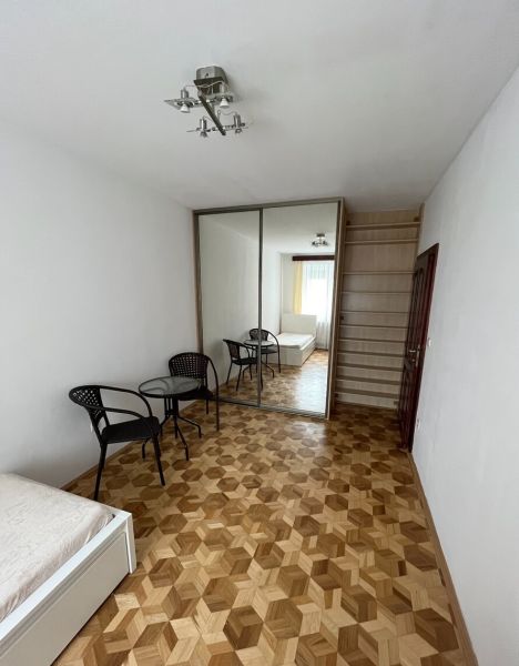 Priestranný a kvalitne zariadený 3-izbový byt – Bratislava, Petržalka - Izba s posteľou, zrkadlovou skriňou, stoličkami, stolíkom a podlahou s dreveným dekorom.