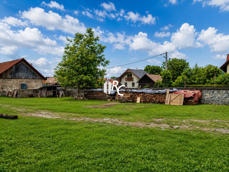 Stavebný pozemok 651 m² v obci Belá-Dulice – tichá lokalita - Pozemky na bývanie v Belá-Duliciach s trávnikom a drevárňou v pozadí.