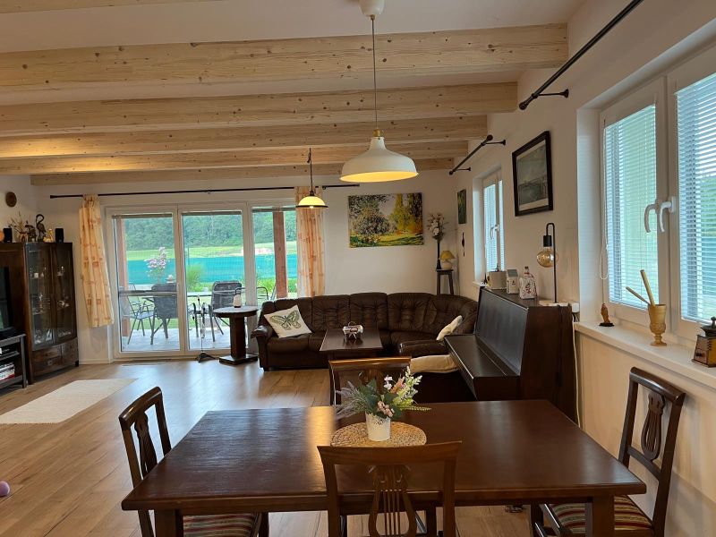 Novostavba 5 izbového rodinného domu v Jarku - Obývacia izba s koženou sedačkou, dreveným stropom a podlahou s dreveným dekorom v rodinnom dome.