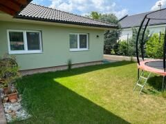 Novostavba 5 izbového rodinného domu v Jarku - Záhrada rodinného domu v Jarku so zeleným trávnikom a trampolínou.