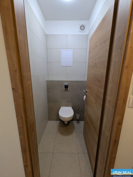 MODERNÁ ZARIADENÁ NOVOSTAVBA  takmer v centre - MAHULANKA - Toaleta v 2-izbovom byte s keramickými obkladmi a podlahou s dreveným dekorom.