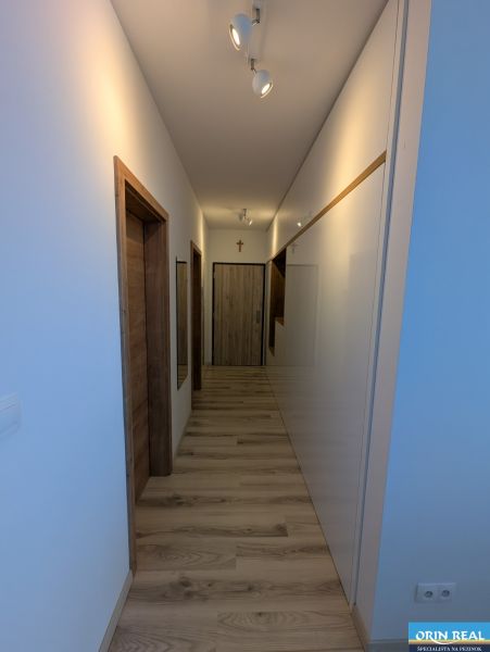 MODERNÁ ZARIADENÁ NOVOSTAVBA  takmer v centre - MAHULANKA - Chodba v 2-izbovom byte s podlahou s dreveným dekorom a bielymi stenami.