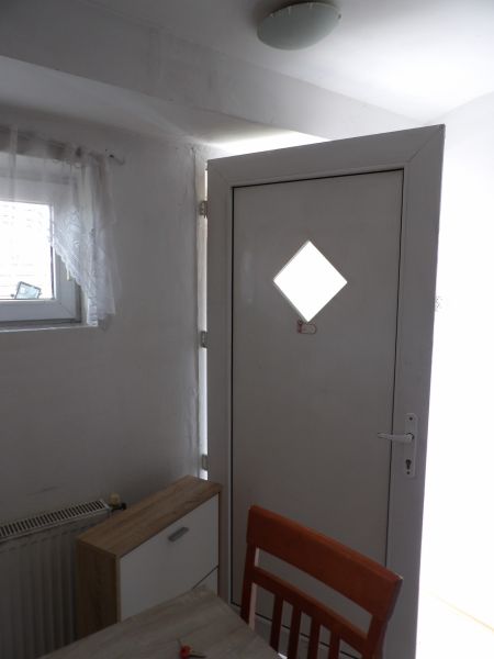 Nájomné bývanie v centre Serede - Vchodové dvere v 2-izbovom byte s dreveným dekorom komody a stoličky.