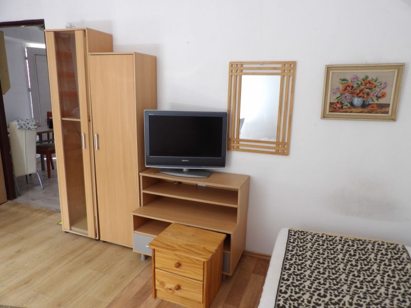Nájomné bývanie v centre Serede - Televízor na nízkej skrinke, skriňa a zrkadlo v 2-izbovom byte s podlahou s dreveným dekorom.