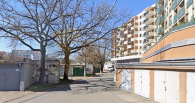 Garáž na ul. Teslova, Ružinov - Garáže na Teslovej ulici v Bratislave - Ružinove, obklopené stromami a bytovkami.