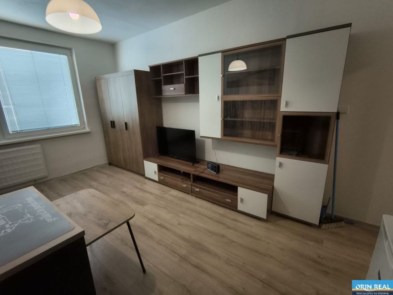 KOMPLET ZARIADENÁ GARSÓNKA PRI PLAVÁRNI - Garsónka s podlahou s dreveným dekorom, skrinkami a televízorom.