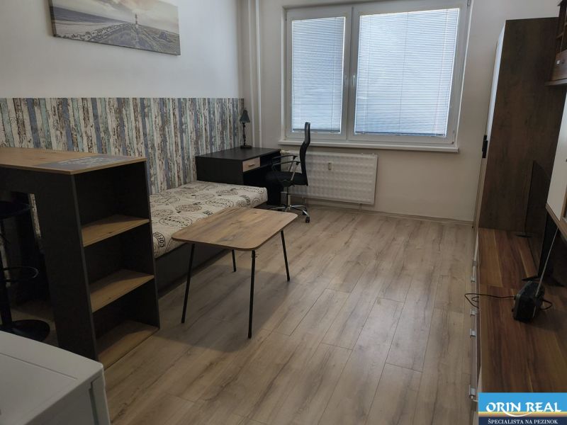 KOMPLET ZARIADENÁ GARSÓNKA PRI PLAVÁRNI - Garsónka s podlahou s dreveným dekorom, pracovným stolom a pohovkou.