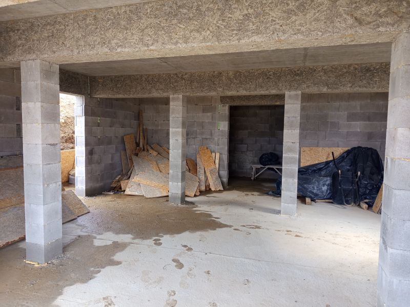 NA PREDAJ - Necpaly - zrubový dom (hrubá stavba) k dokončeniu - Nedokončený interiér rodinného domu s betónovými stenami a rozličným stavebným materiálom.