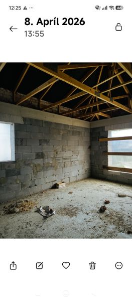 Príbovce -rodinný dom /Bungalov/ Hrubá stavba - Interiér nedokončeného rodinného domu s pohľadom na drevené trámy a betónové steny.