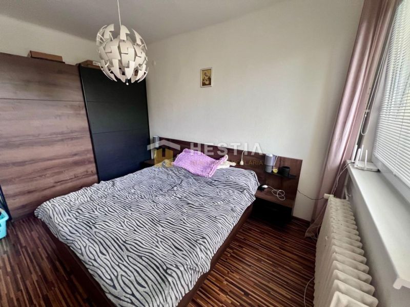 2 izbový byt na prenájom s balkónom na Kalinčiakovej, voľný od 01.10.2 - Spálňa v 2-izbovom byte s podlahou s dreveným dekorom, posteľou a skrinkou.