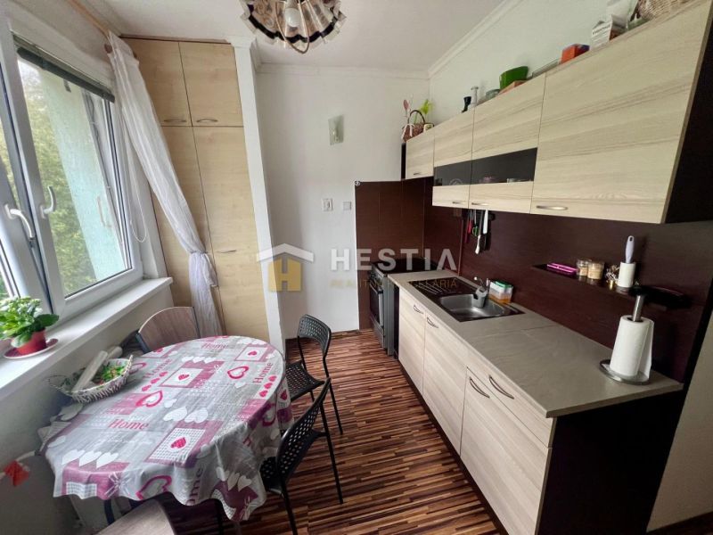 2 izbový byt na prenájom s balkónom na Kalinčiakovej, voľný od 01.10.2 - Kuchyňa v 2-izbovom byte s podlahou s dreveným dekorom a jedálenským stolom.