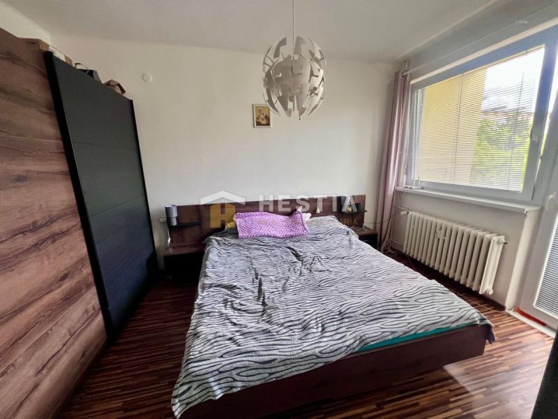 2 izbový byt na prenájom s balkónom na Kalinčiakovej, voľný od 01.10.2 - Spálňa v 2-izbovom byte s podlahou s dreveným dekorom a veľkým oknom.
