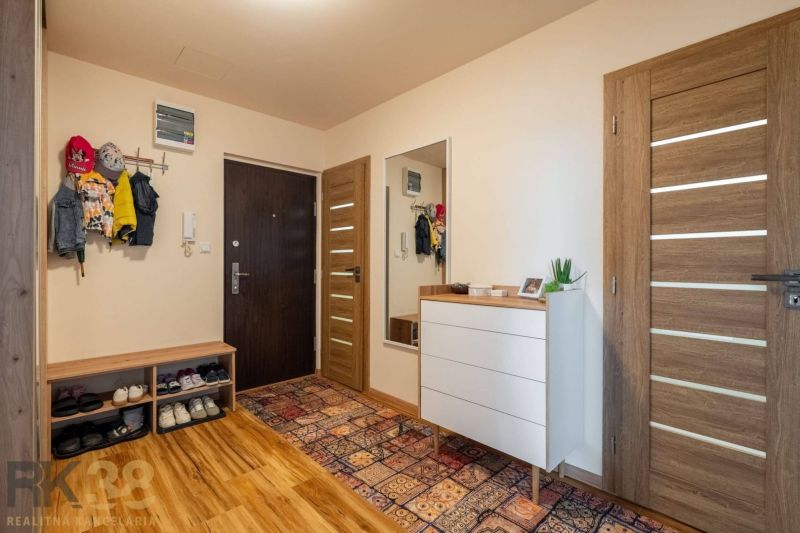Kompletne zrekonštruovaný 3-izbový byt s priestranným balkónom - Vstupná hala v 3-izbovom byte s podlahou s dreveným dekorom a farebným kobercom.