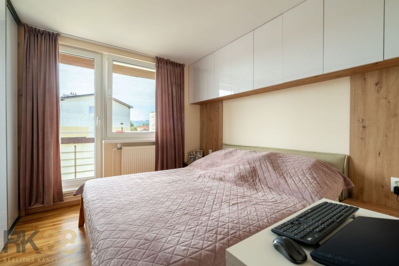 Kompletne zrekonštruovaný 3-izbový byt s priestranným balkónom - Spálňa s ružovou prikrývkou v 3-izbovom byte, vybavená podlahou s dreveným dekorom.