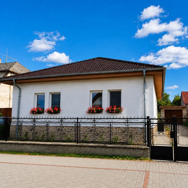 Na predaj zrekonštruovaný 4-izbový rodinný dom v Šalgočke  - Rodinný dom v Šalgočke s bielou fasádou, okennými kvetmi a valbovou strechou.
