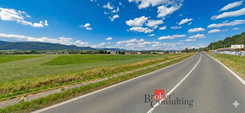 Investičná príležitosť: Komerčný pozemok 8 861 m² s platnou ÚPI v Hlin - Hliník nad Hronom, Pozemky - komerčné, zelené lúk pri ceste obklopenej kopcami a budovami.